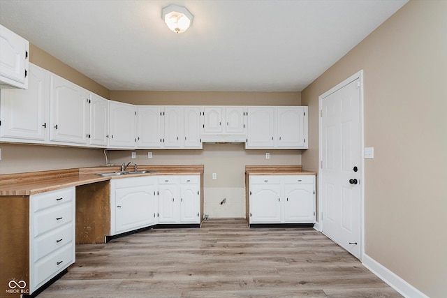 kitchen featuring sink, white cabinets, and light wood-type flooring