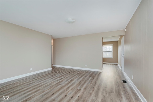 unfurnished room with light hardwood / wood-style floors and wooden walls