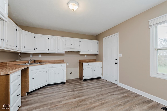 kitchen with sink, white cabinets, and light hardwood / wood-style floors