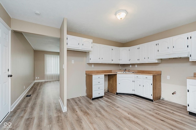 kitchen with wood counters, light hardwood / wood-style flooring, white cabinets, and sink