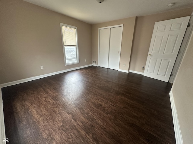 unfurnished bedroom with dark hardwood / wood-style flooring and a closet