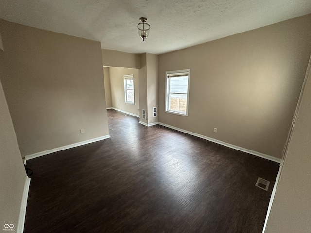 empty room featuring dark hardwood / wood-style flooring and a textured ceiling