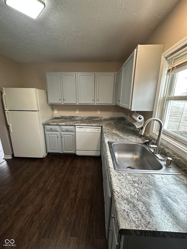 kitchen featuring dark hardwood / wood-style flooring, white appliances, a textured ceiling, sink, and white cabinetry