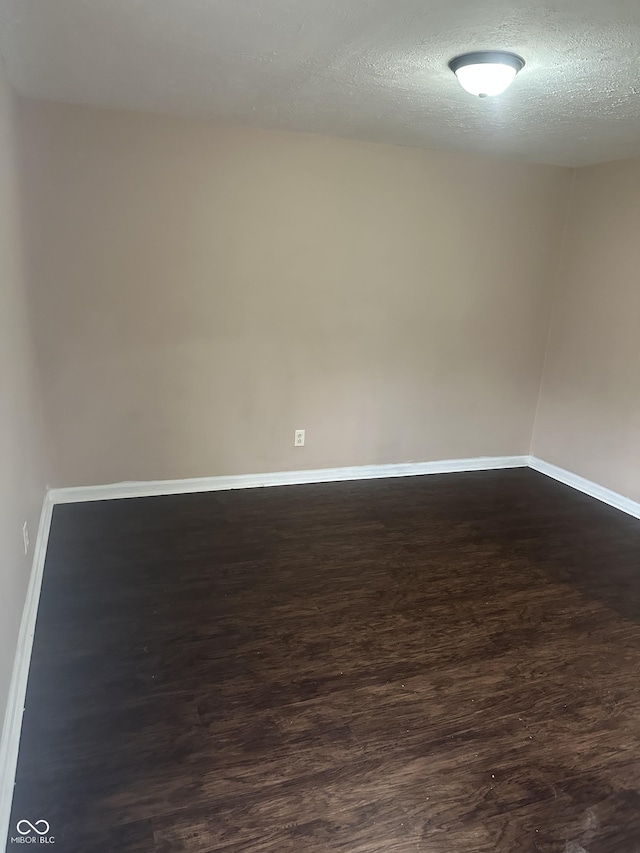 spare room with a textured ceiling and dark hardwood / wood-style flooring