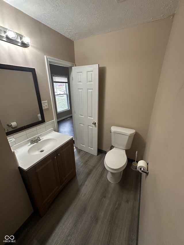 bathroom with hardwood / wood-style floors, vanity, a textured ceiling, and toilet