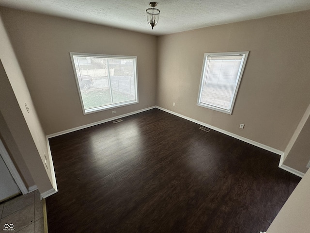 spare room featuring dark hardwood / wood-style flooring and a textured ceiling