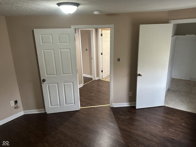 unfurnished bedroom with dark hardwood / wood-style floors and a textured ceiling