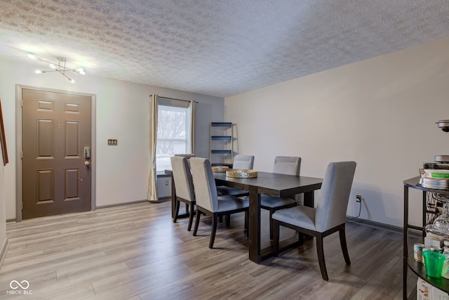 dining space featuring a textured ceiling, hardwood / wood-style flooring, and an inviting chandelier