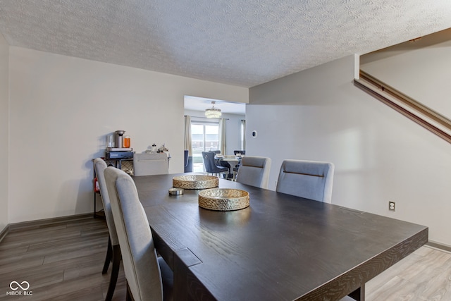 dining area with wood-type flooring and a textured ceiling