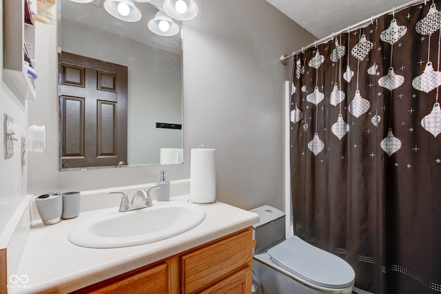 bathroom with vanity, toilet, and a textured ceiling