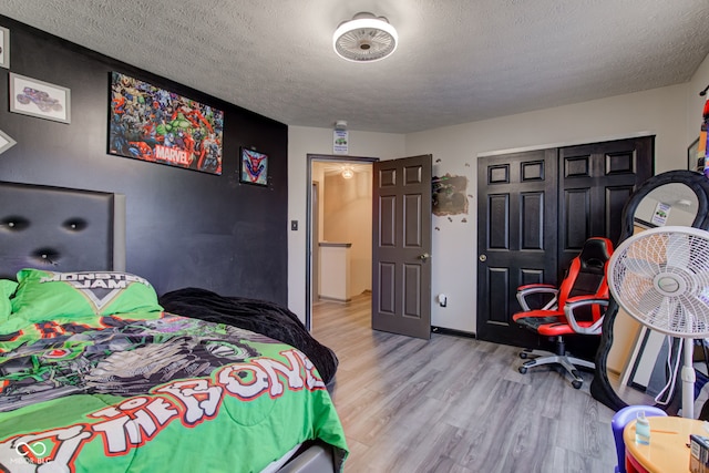 bedroom featuring a textured ceiling, light hardwood / wood-style floors, and a closet