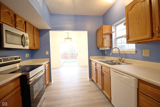 kitchen featuring sink, dishwasher, electric range oven, light hardwood / wood-style floors, and decorative light fixtures