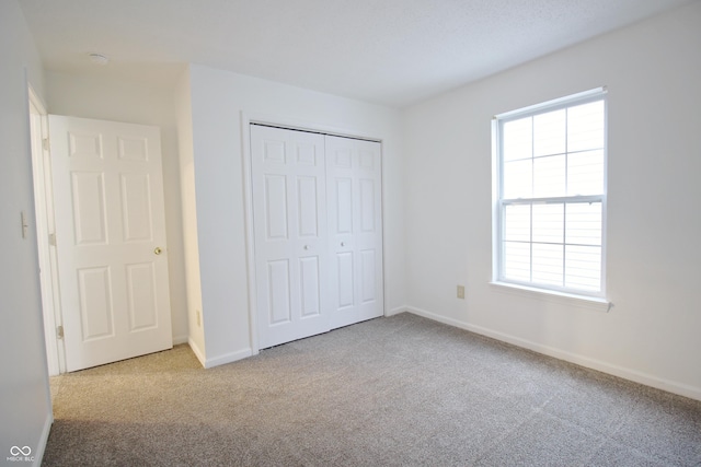 unfurnished bedroom with light colored carpet and a closet