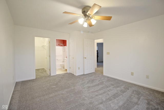 unfurnished bedroom with carpet, ensuite bathroom, a walk in closet, ceiling fan, and a closet