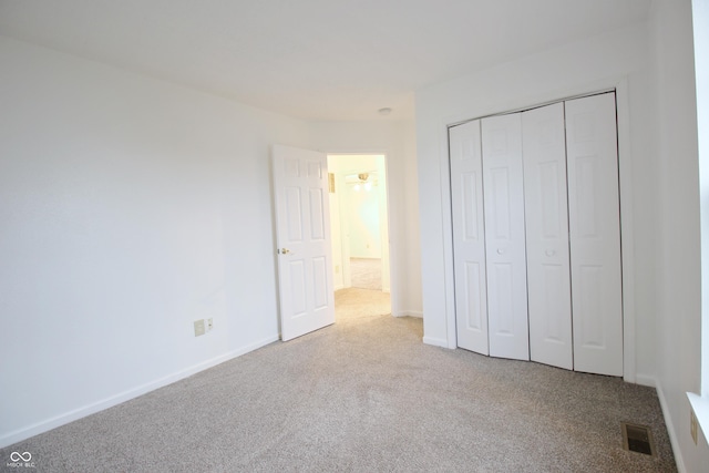 unfurnished bedroom with a closet and light colored carpet