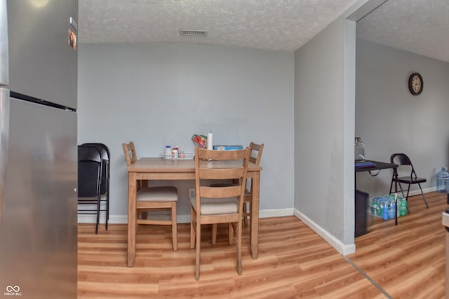 dining space with wood-type flooring and a textured ceiling