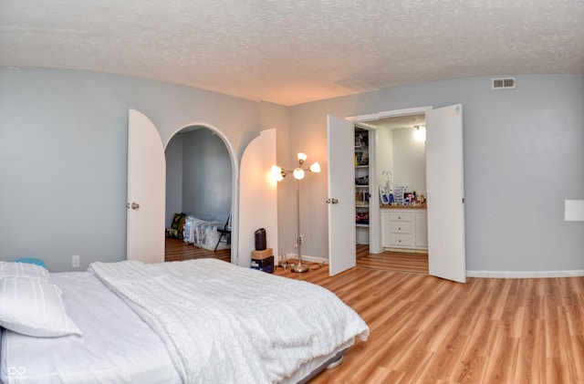 bedroom featuring a textured ceiling and light hardwood / wood-style flooring