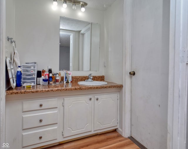 bathroom featuring wood-type flooring, vanity, and a textured ceiling