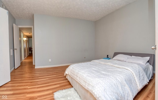 bedroom with a textured ceiling and light wood-type flooring