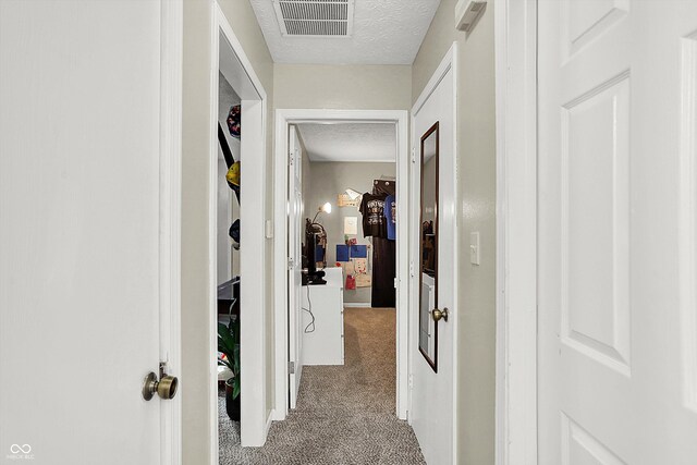 hallway with light carpet and a textured ceiling