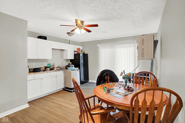 dining room with a textured ceiling, light wood-type flooring, and ceiling fan