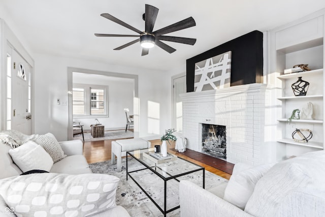 living room featuring a fireplace, light wood-type flooring, and ceiling fan