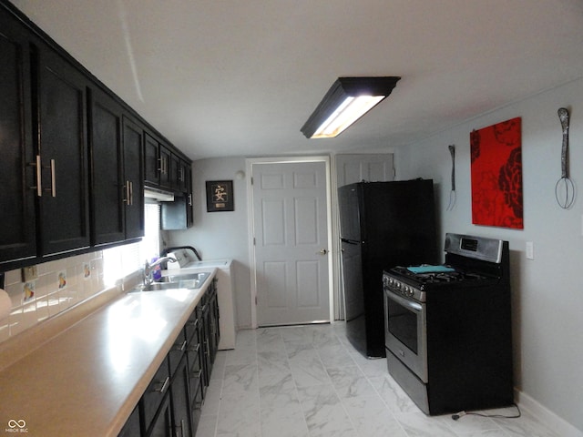 kitchen featuring decorative backsplash, black fridge, sink, and stainless steel gas range