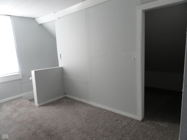 carpeted empty room featuring vaulted ceiling