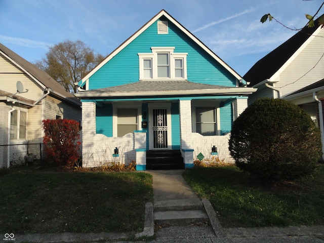 bungalow featuring covered porch and a front lawn