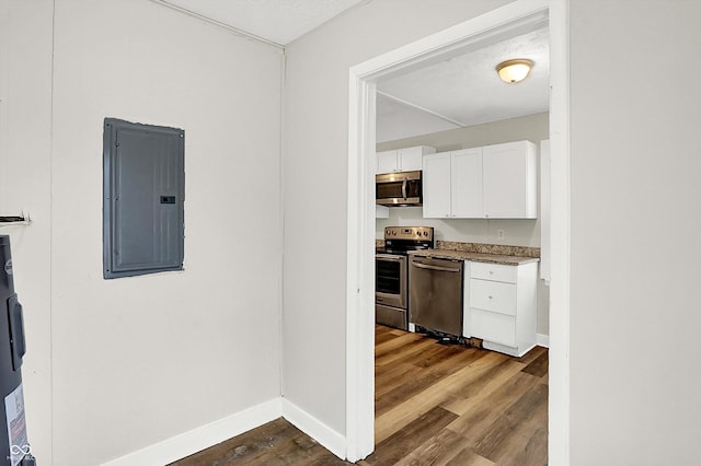 kitchen featuring white cabinets, wood-type flooring, appliances with stainless steel finishes, and electric panel