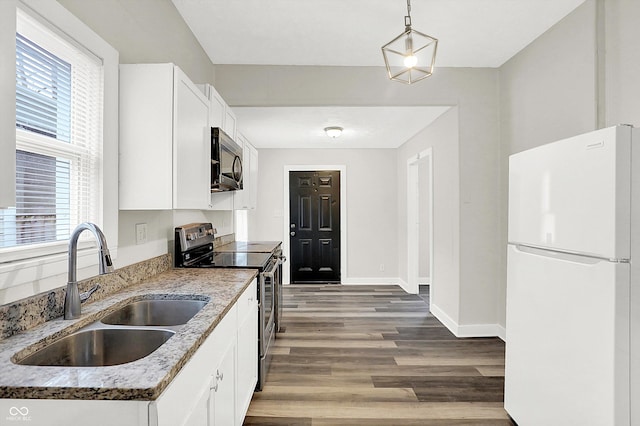 kitchen with pendant lighting, sink, appliances with stainless steel finishes, light stone countertops, and white cabinets