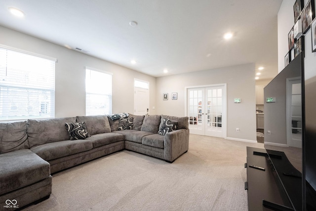 living room featuring plenty of natural light, light carpet, and french doors