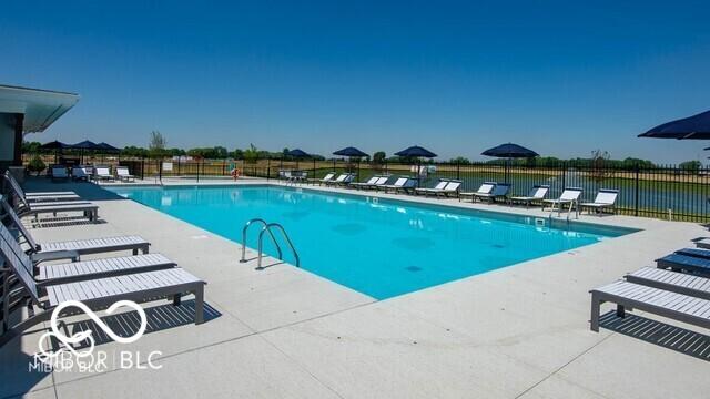 view of swimming pool with a patio area and a water view