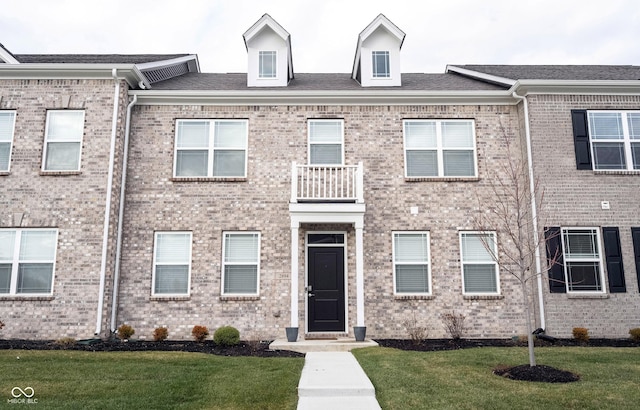 multi unit property featuring a balcony and a front yard