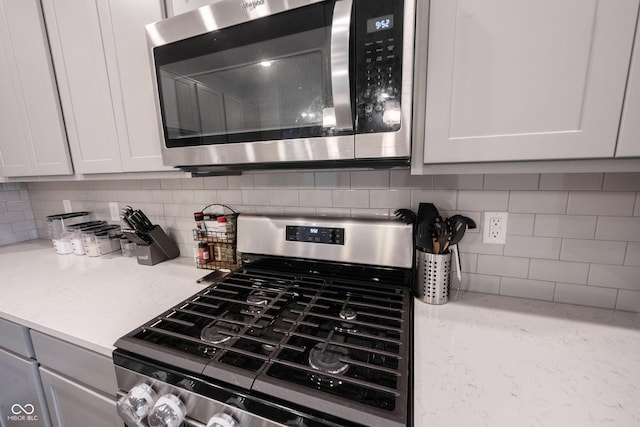 kitchen featuring white cabinets, decorative backsplash, and stainless steel appliances