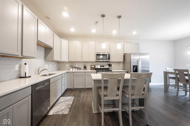 kitchen with backsplash, stainless steel appliances, dark wood-type flooring, sink, and hanging light fixtures