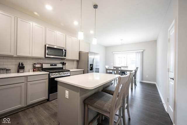 kitchen featuring a center island, backsplash, hanging light fixtures, dark hardwood / wood-style floors, and appliances with stainless steel finishes