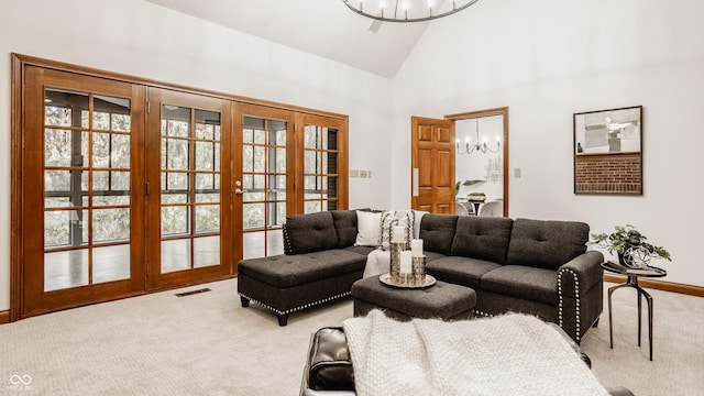 living area featuring a notable chandelier, carpet flooring, high vaulted ceiling, and visible vents