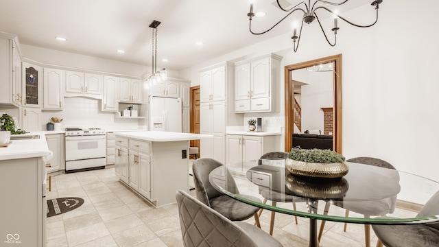 kitchen featuring decorative backsplash, white appliances, a center island, and light countertops