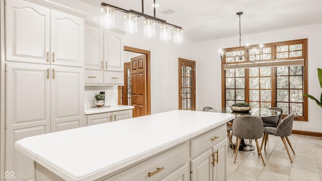 kitchen with a center island, white cabinetry, light countertops, a chandelier, and hanging light fixtures