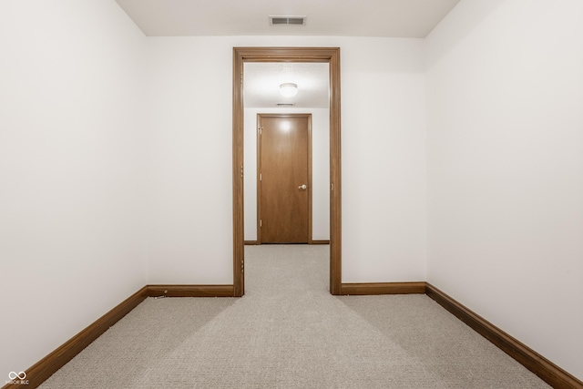 hall with visible vents, baseboards, and carpet