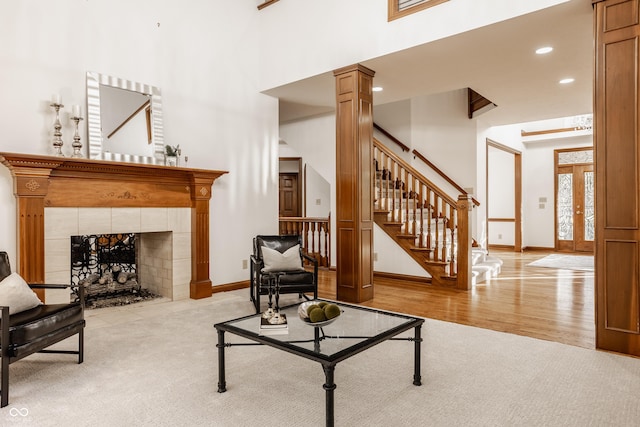 living area with baseboards, wood finished floors, stairs, and ornate columns