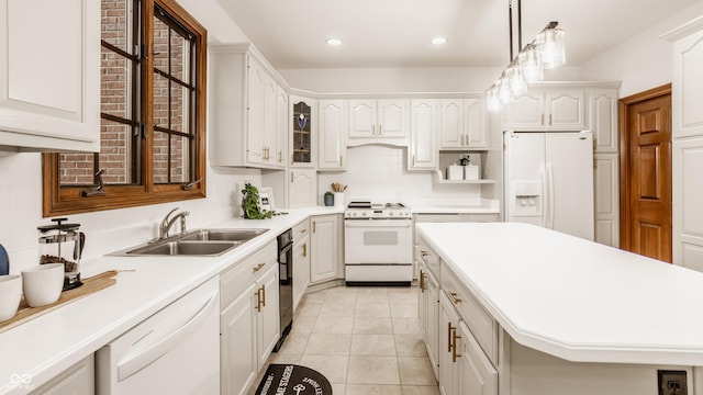 kitchen with tasteful backsplash, decorative light fixtures, light countertops, white appliances, and a sink