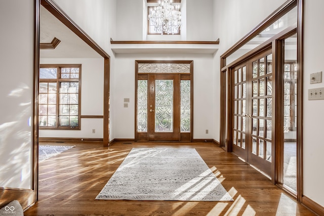 entrance foyer featuring a towering ceiling, french doors, baseboards, and wood finished floors