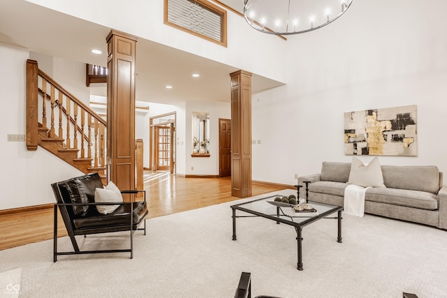 living room with light wood-style flooring, baseboards, stairs, and ornate columns