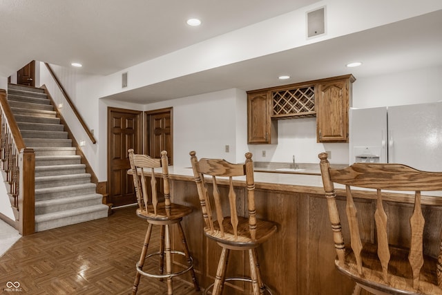 bar with visible vents, recessed lighting, white fridge with ice dispenser, wet bar, and stairs