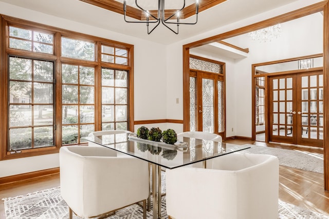 interior space with wood finished floors, a notable chandelier, french doors, and baseboards