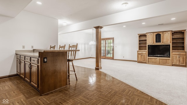 kitchen with a kitchen breakfast bar, recessed lighting, a peninsula, baseboards, and ornate columns