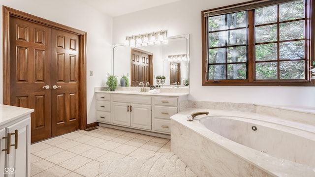 bathroom with tile patterned floors, a healthy amount of sunlight, a bath, and vanity