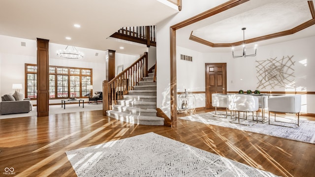 interior space with visible vents, stairs, a tray ceiling, decorative columns, and an inviting chandelier